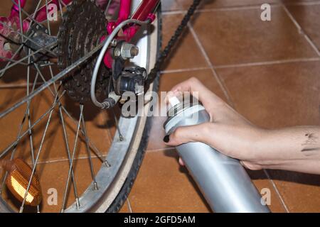 vista di una mano di una ragazza che pulisce la sua moto con uno straccio e spray Foto Stock