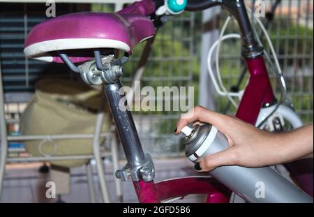 vista di una mano di una ragazza che pulisce la sua moto con uno straccio e spray Foto Stock