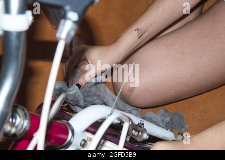 vista di una mano di una ragazza che pulisce la sua moto con uno straccio e spray Foto Stock