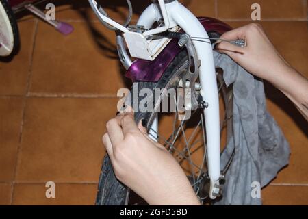 vista di una mano di una ragazza che pulisce la sua moto con uno straccio e spray Foto Stock