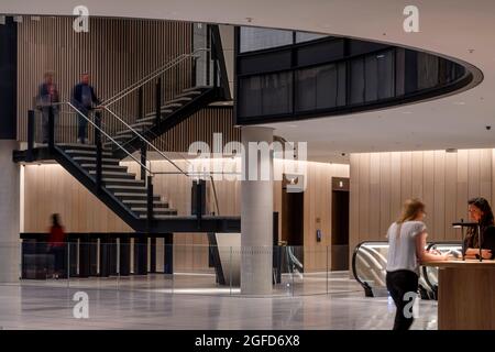 Scala atrio e ascensore lobby. 100 Liverpool Street, Londra, Regno Unito. Architetto: Hopkins Architects Partnership LLP, 2021. Foto Stock