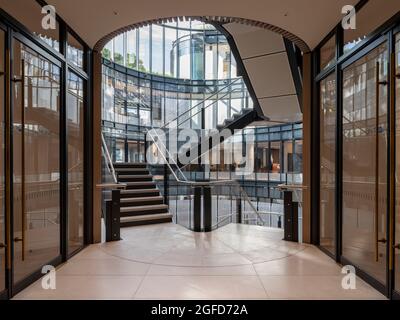 Hall con ascensore e vista sull'atrio. 100 Liverpool Street, Londra, Regno Unito. Architetto: Hopkins Architects Partnership LLP, 2021. Foto Stock