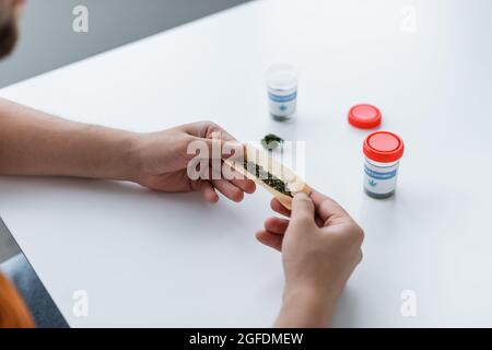 vista parziale dell'uomo che si articolare con cannabis medica secca a casa Foto Stock