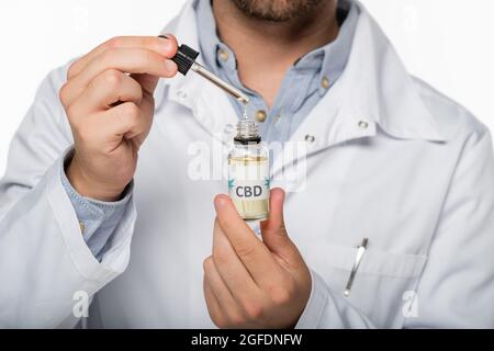 vista parziale del medico con flaconcino di olio di cannabis isolato su bianco Foto Stock