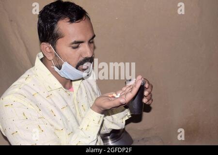 Giovane rurale con pillole e bicchiere d'acqua nelle sue mani, sta per prendere qualche medicina, periodo Corona Foto Stock