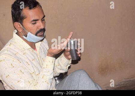 Giovane rurale con pillole e bicchiere d'acqua nelle sue mani, sta per prendere qualche medicina, periodo Corona Foto Stock