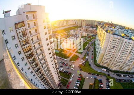 Vista dall'alto del balcone al tramonto e sul cortile del paesaggio cittadino con auto e parcheggio Foto Stock