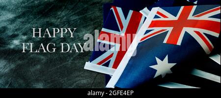 primo piano di alcune bandiere australiane e il testo happy australia day su sfondo grigio scuro, in formato panoramico da utilizzare come banner web o intestazione Foto Stock