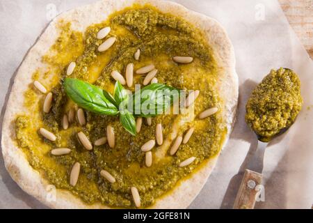 Preparazione della pizza cruda con salsa di pesto Foto Stock