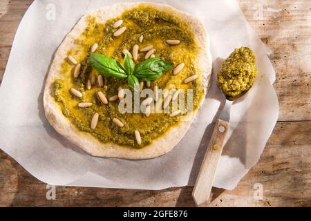 Preparazione della pizza cruda con salsa di pesto Foto Stock