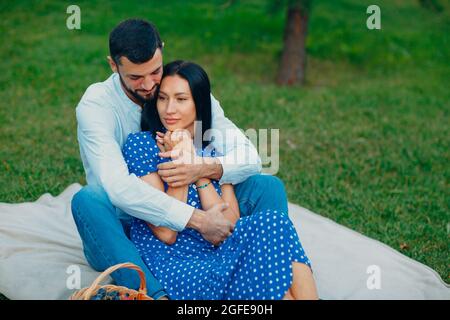 Giovane donna adulta e uomo abbracciante coppia pic-nic al prato verde in parco Foto Stock