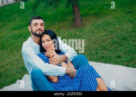 Giovane donna adulta e uomo abbracciante coppia pic-nic al prato verde in parco Foto Stock