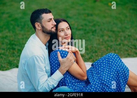 Giovane donna adulta e uomo abbracciante coppia pic-nic al prato verde in parco Foto Stock