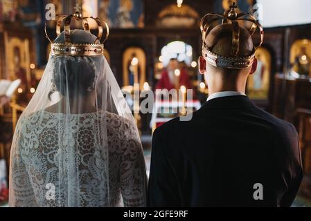 Sposa e sposo indossando corone durante una cerimonia nuziale in chiesa Foto Stock