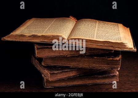 Pila di vecchi libri ebrei shabby indossati in pelle che si legano al buio. Apri pagina di Torah. Primo piano. Messa a fuoco selettiva. Tasto basso Foto Stock