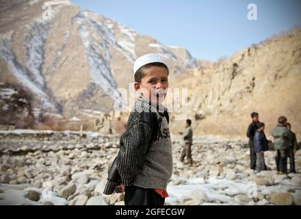 Un bambino afghano sorride giocando accanto al fiume nel distretto di Dara della provincia di Panjshir, Afghanistan, 3 gennaio 2010. Foto Stock