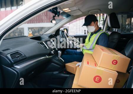 Selezionare fuoco una casella, UN addetto alla consegna che utilizza un lettore di carte di credito. Nel furgone con pacchi all'esterno del magazzino. Consegna Foto Stock