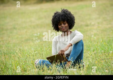 Giovane donna che usa un tablet digitale nel parco pubblico Foto Stock