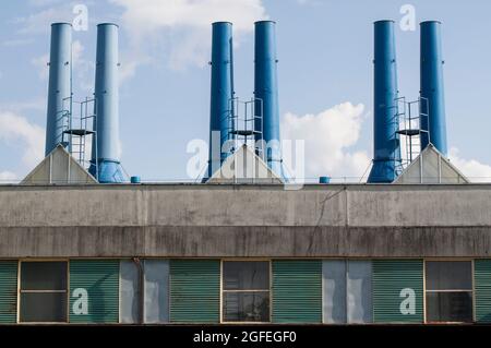 Una visione industriale di una vecchia fabbrica con camini contro il cielo Foto Stock