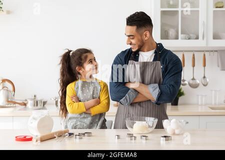 Piccolo aiutatore. Ritratto di padre arabo e figlia cottura in cucina Foto Stock