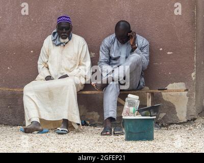 Joal-Fadiouth, Senegal - Jan, 2019: Uomini sulla strada dell'isola di Seashell. Comune e comune della Regione Thiès, Petite Côte del Senegal. Africa. Foto Stock