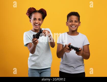 Emotivo fratello afroamericano e sorella con i joystick Foto Stock