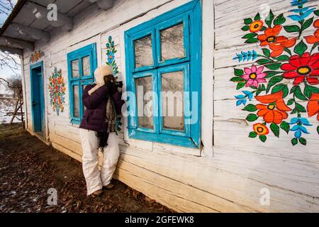 Zalipie, Polonia - Gennaio 06, 2017: Donna fare una foto nel piccolo villaggio Zalipie con la colorata e dipinta a mano case. La Polonia. Pasqua in Europa. Foto Stock