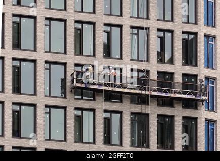 Lavoratori edili che installano nuove finestre in un edificio aziendale a Brooklyn, New York Foto Stock