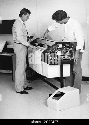Austin Texas USA, circa 1992: I tecnici di riparazione lavorano su apparecchiature di disegno di computer in un ufficio di architettura. ©Bob Daemmrich Foto Stock