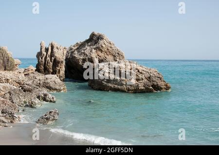 Piccola Cove nel Mediterraneo, Nerja, Costa del Sol, Provincia di Malaga, Andalusia, Spagna. Rocce nel mare. Acqua limpida turchese. Foto Stock