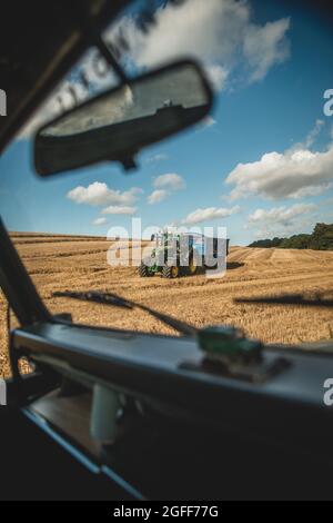 Canterbury, Kent, Regno Unito. 25 agosto 2021. Una mietitrebbia raccoglie grano sotto cieli soleggiati, vicino a Canterbury, nella campagna del Kent. Credit: Kevin Bennett/Alamy Live News Foto Stock