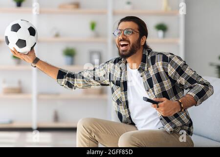 Felice uomo medio-orientale football fan guardare la partita in TV Foto Stock
