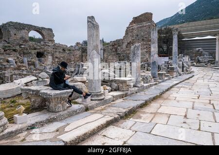 Selcuk, Izmir, Turchia - 03.09.2021: Una donna turistica seduta su pietre di Casa privata brothel in Efeso rovine, storico antico archeologico romano Foto Stock