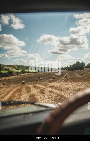 Canterbury, Kent, Regno Unito. 25 agosto 2021. Una mietitrebbia raccoglie grano sotto cieli soleggiati, vicino a Canterbury, nella campagna del Kent. Credit: Kevin Bennett/Alamy Live News Foto Stock