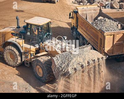 La pala caricatrice gommata carica il cassone ribaltabile con terreno Foto Stock