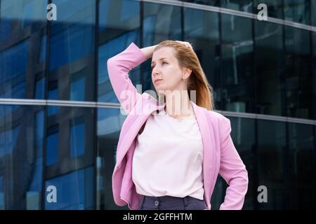 Giovane bella donna bionda con capelli lunghi in abiti rosa ed eleganti Foto Stock