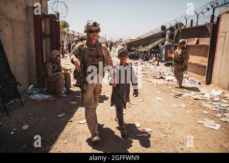 Una Marina degli Stati Uniti con il comando centrale di risposta alla crisi (SPMAGTF-CR-CC) scorta un bambino alla sua famiglia durante un'evacuazione all'Aeroporto Internazionale Hamid Karzai di Kabul, Afghanistan, 24 agosto 2021. I membri di servizio STATUNITENSI e le forze di coalizione stanno assistendo il Dipartimento di Stato con un'operazione di evacuazione non combattente (NEO) in Afghanistan. Credito obbligatorio: Victor Mancilla/US Marine Corps via CNP Foto Stock