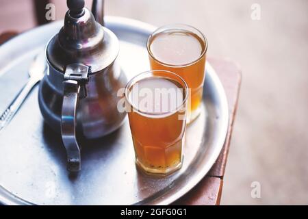 Tè marocchino, bollitore e bicchiere di tè fresco, Essaouira, Marocco Foto Stock