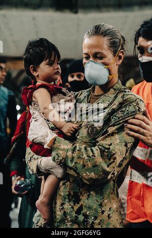 Sigonella, Italia. 22 agosto 2021. Il comandante della Marina degli Stati Uniti, Anna Wood, assiste gli evacuati quando sbarcano da un aereo della forza aerea C-17 Globemaster III degli Stati Uniti dopo l'arrivo alla base aerea navale di Sigonella il 22 agosto 2021 a Sigonella, Italia. NAS Sigonella fornisce alloggio temporaneo per gli evacuati dall'Afghanistan come parte dell'operazione Rifugi Alleati. Credit: Planetpix/Alamy Live News Foto Stock