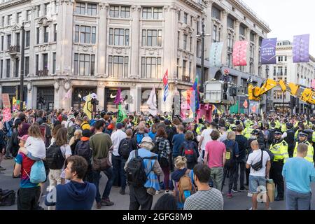 Oxford Circus, Londra, Regno Unito. 25 agosto 2021. I manifestanti del cambiamento climatico della ribellione di estinzione occupano Oxford Circus alla ribellione impossibile. Presenza pesante della polizia, gru JCB per rimuovere due donne dalla parte superiore della struttura rosa. Credit: Xiu Bao/Alamy Live News Foto Stock