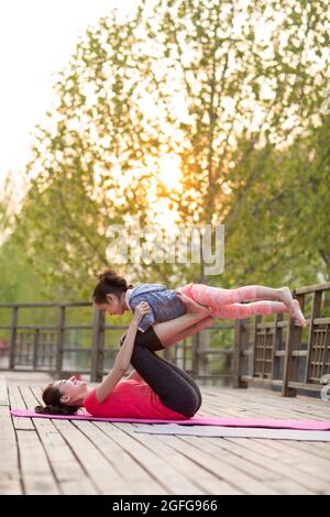 Felice madre e figlia che fanno yoga all'aperto Foto Stock