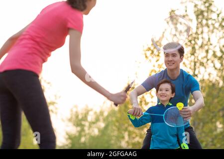 Felice famiglia giovane che gioca badminton nel parco Foto Stock