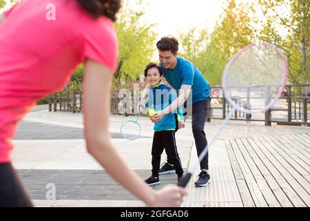 Felice famiglia giovane che gioca badminton nel parco Foto Stock