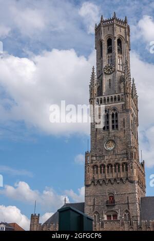 Brugge, Fiandre, Belgio - 3 agosto 2021: Torre di Halletoren Belfry in pietra marrone contro il paesaggio azzurro. Foto Stock