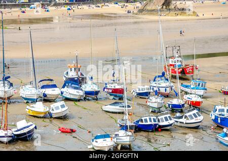 Barche in barca a vela nel porto di Tenby a Pembrokeshire, Galles, con bassa marea. La sabbia è stata rivelata e il mare è completamente fuori, Foto Stock