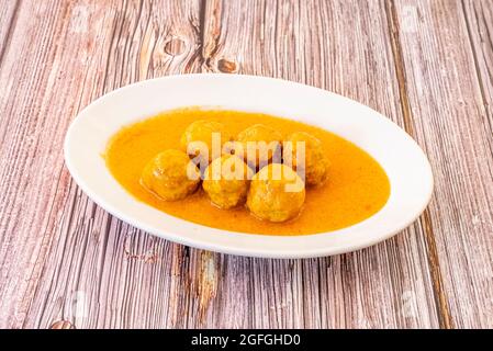 Vassoio bianco con porzione di polpettone stufato in salsa di verdure su tavola di legno Foto Stock