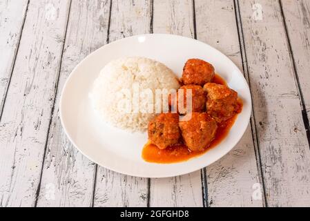 Piatto di polpette in salsa di pomodoro con riso bianco guarnire su piatto bianco e tavola bianca Foto Stock