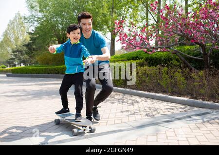 Padre che insegna a suo figlio lo skateboard Foto Stock