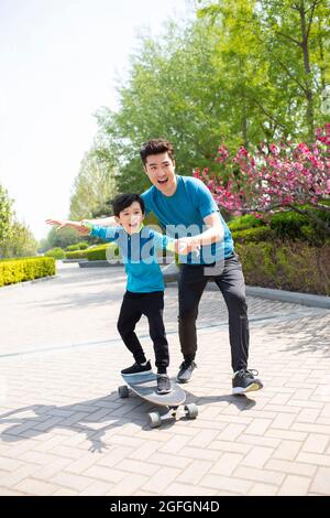 Padre che insegna a suo figlio lo skateboard Foto Stock