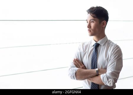 Giovane uomo d'affari che pensa di fronte alla finestra Foto Stock